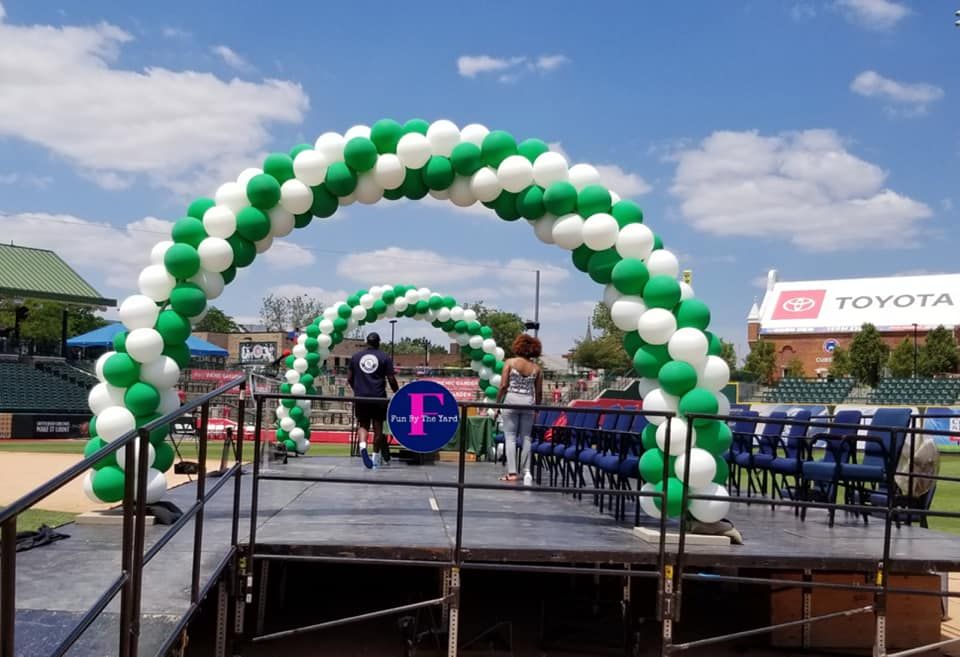 A stage is decorated with green and white balloons.