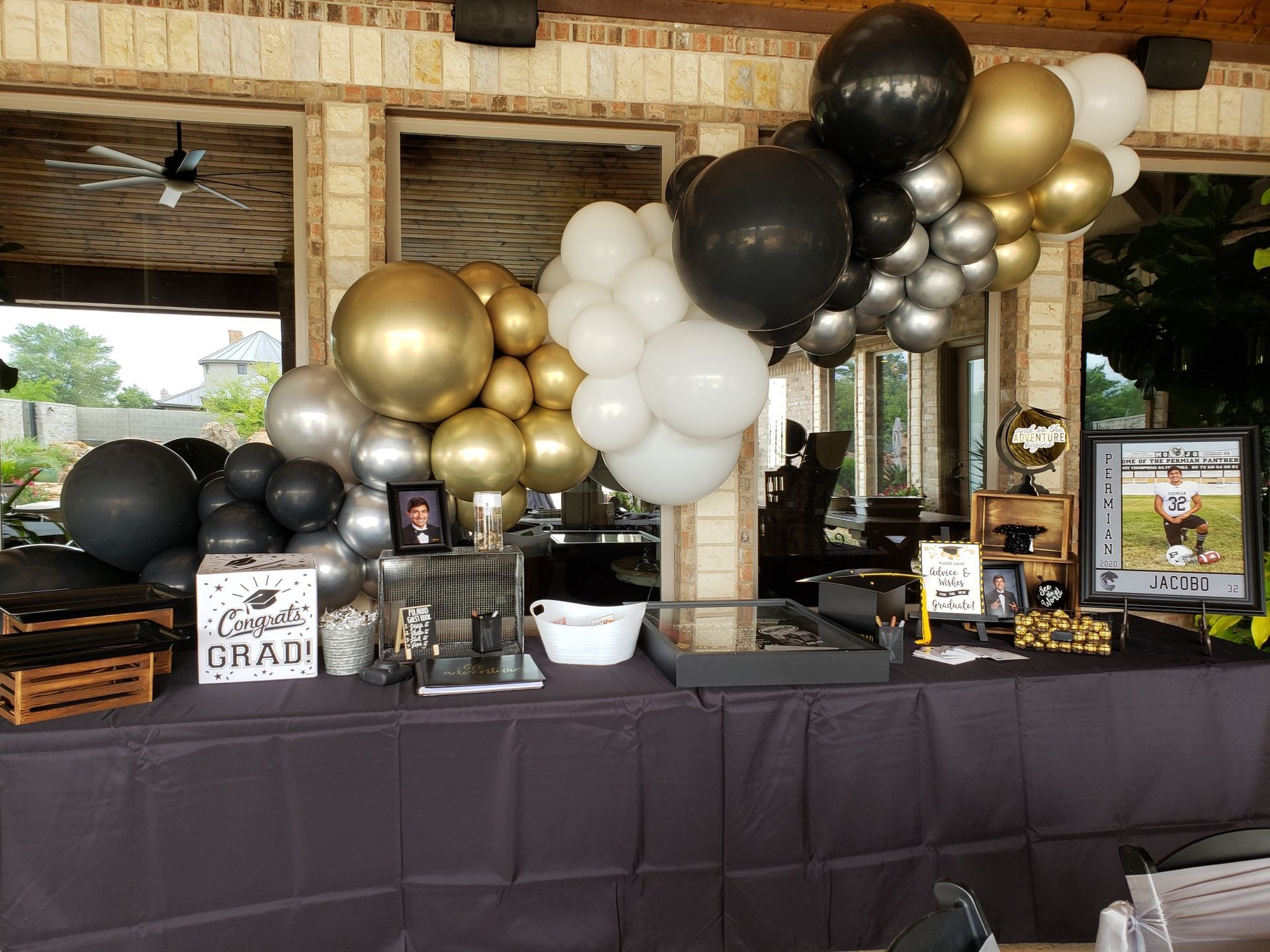 A table decorated with black , gold , and silver balloons for a graduation party.