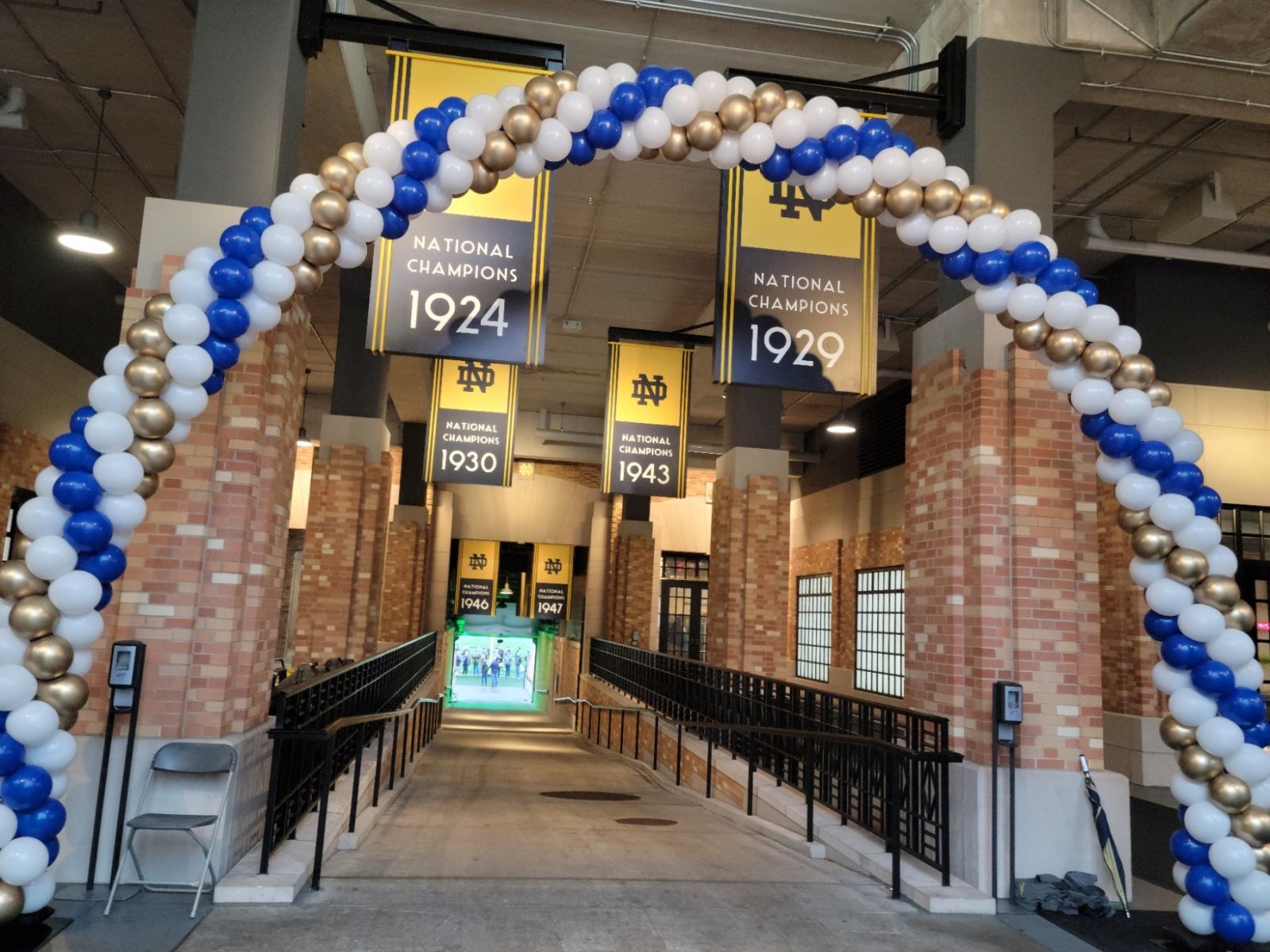 a large arch made of blue , white and gold balloons in front of the Notre Dame tunnel