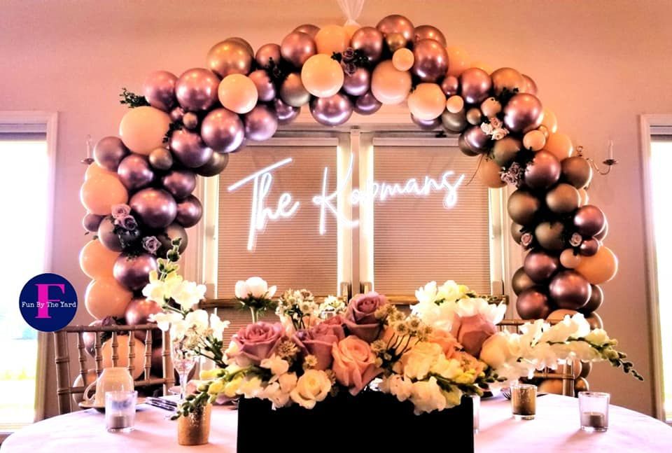 A table with flowers and balloons in front of a sign that says `` the hermans ''.