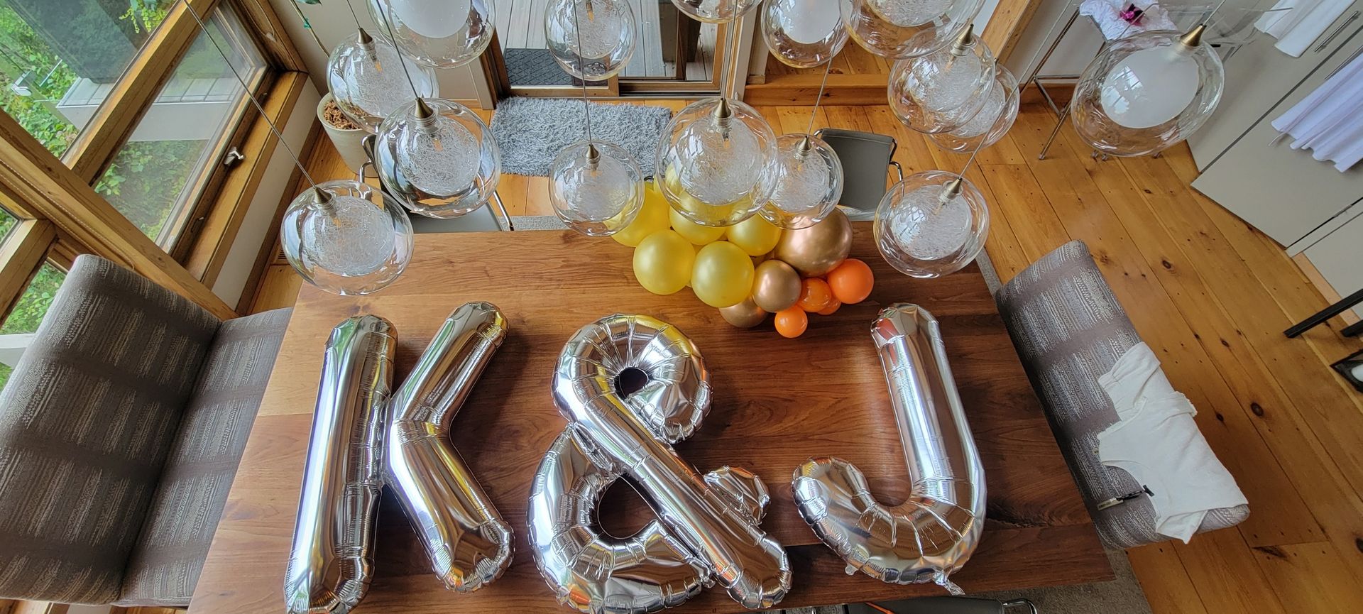 A wooden table with balloons in the shape of the letters k and j on it.