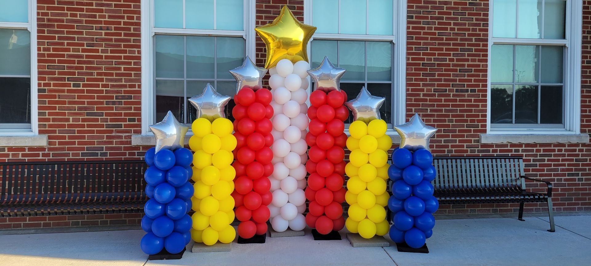 A bunch of balloons are sitting in front of a brick building.