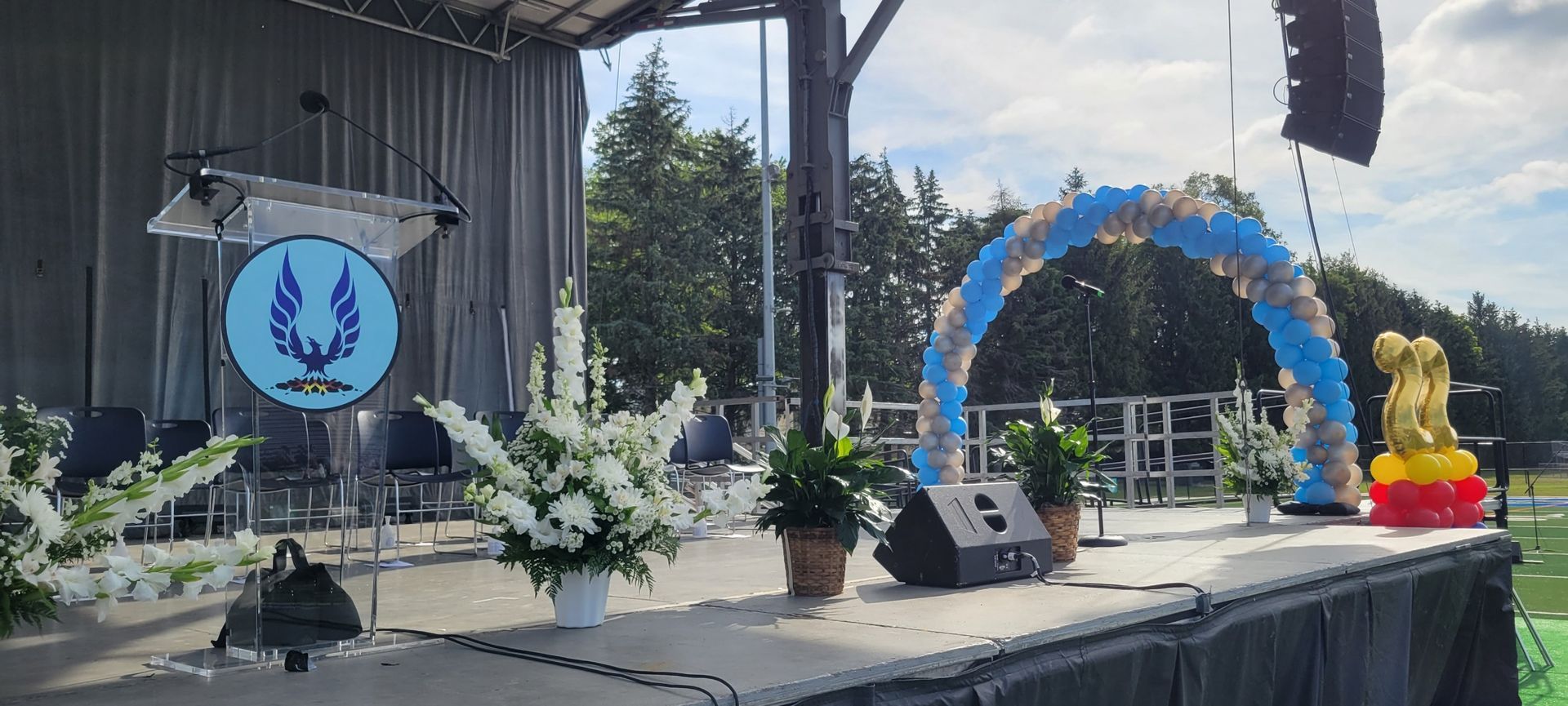 A stage with flowers and balloons on it and a podium.