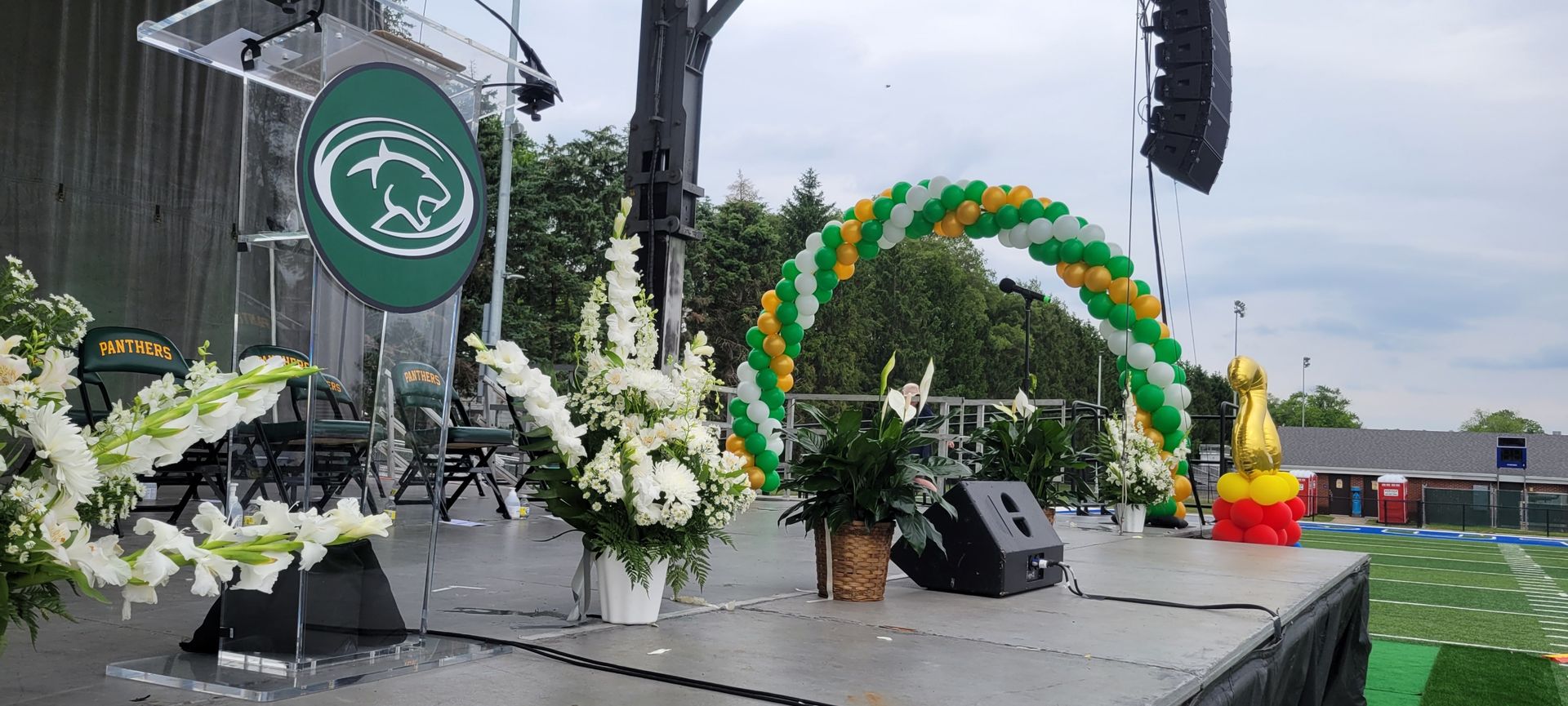 A stage with flowers and balloons on it and a podium.