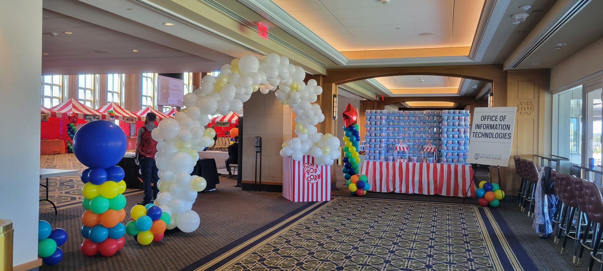 A hallway filled with balloons and a popcorn stand.