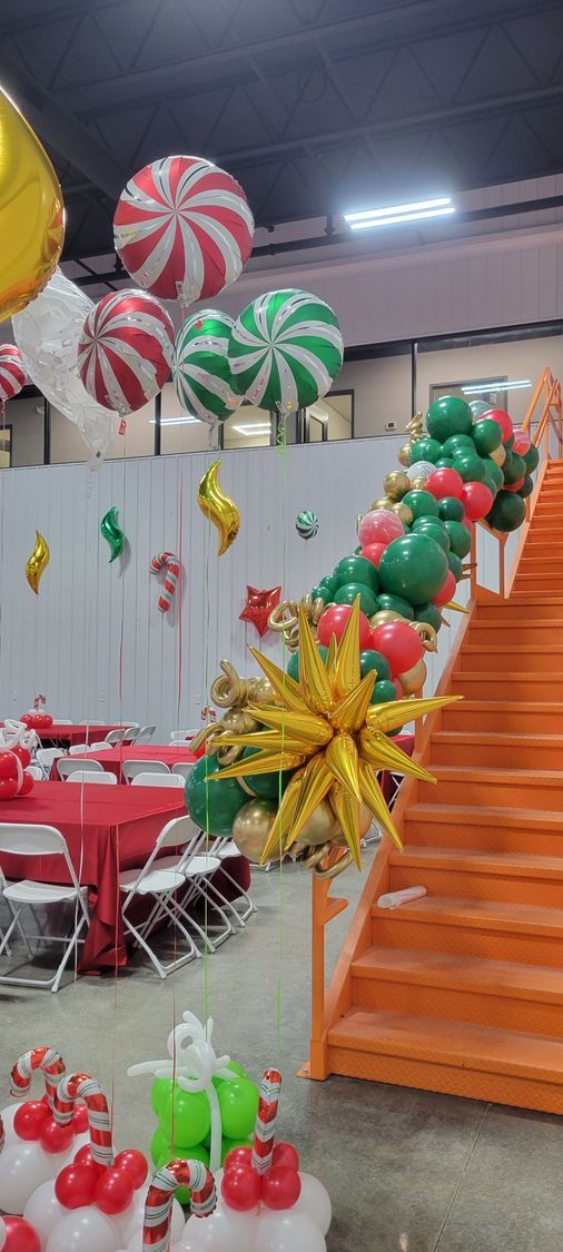 A room decorated for christmas with balloons and stairs.