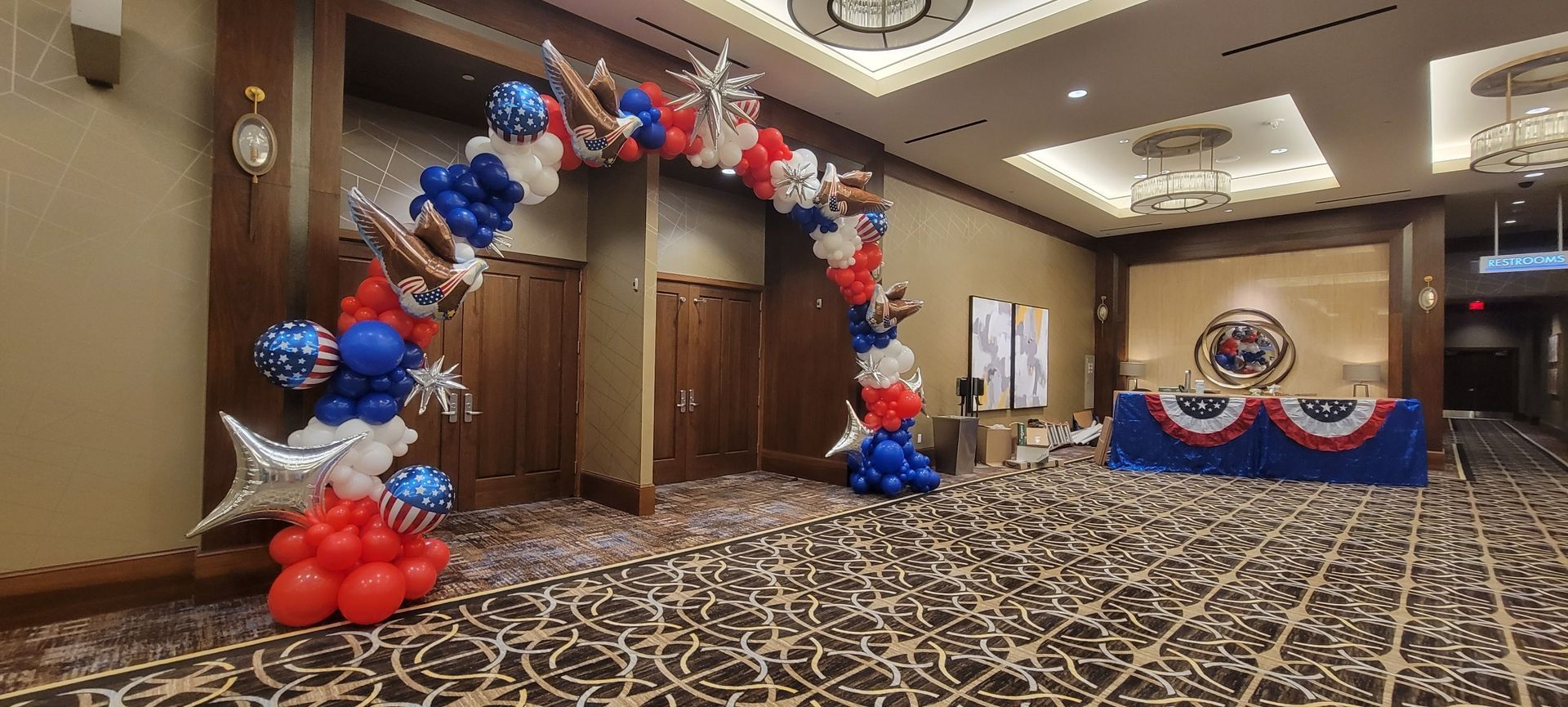A room decorated with red , white and blue balloons. Organic balloon arch