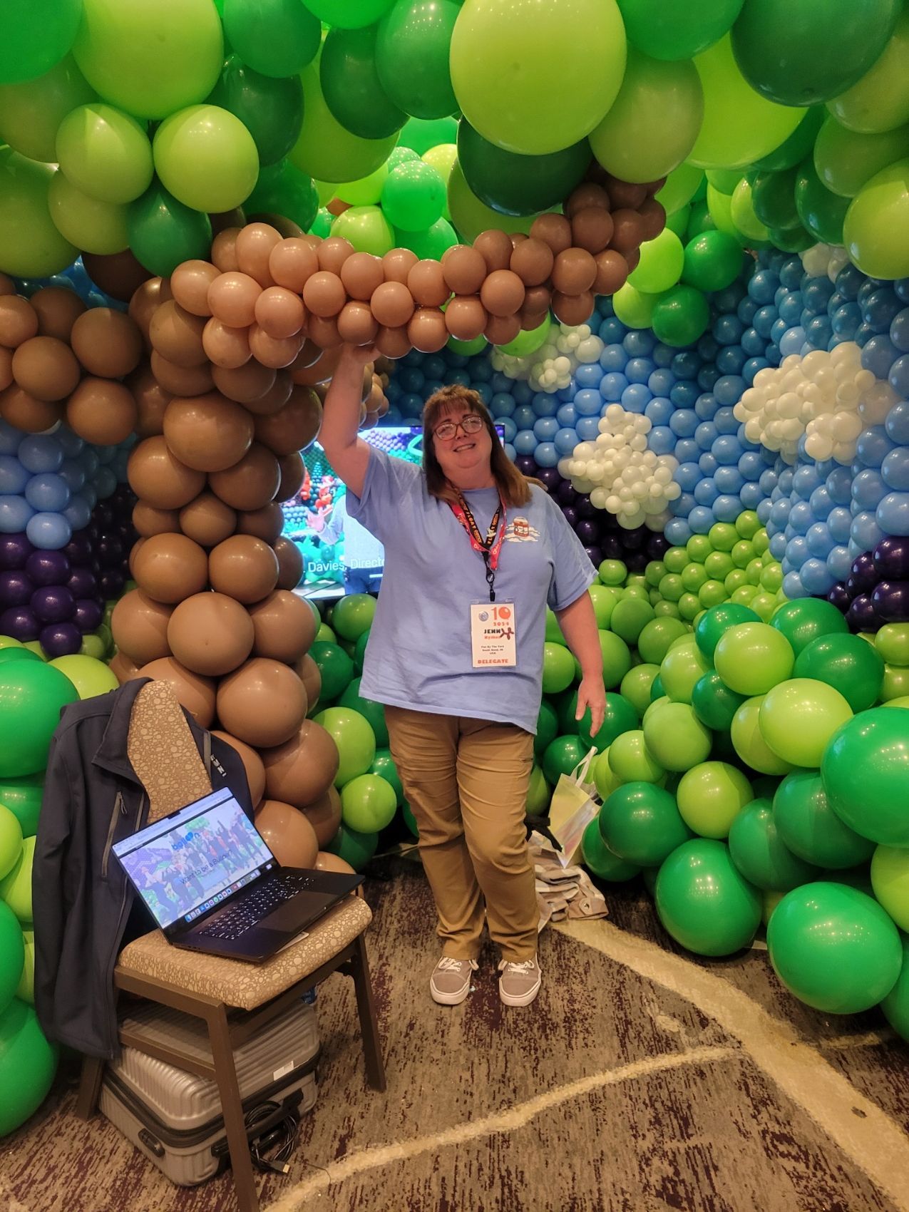 A woman is standing in front of a wall of balloons.