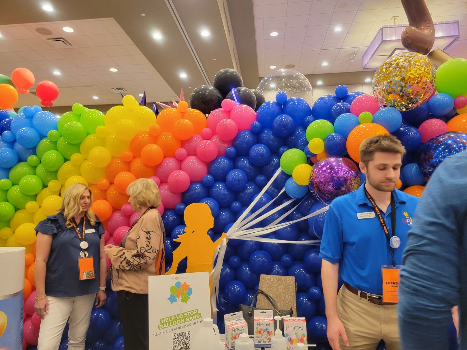 A group of people standing in front of a wall of balloons