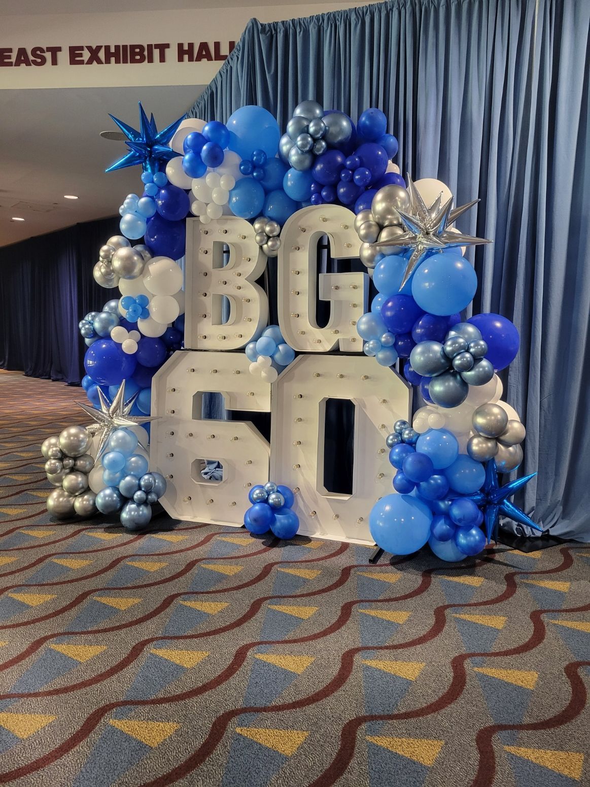 A sign that says `` bg 60 '' is surrounded by blue and silver balloons.