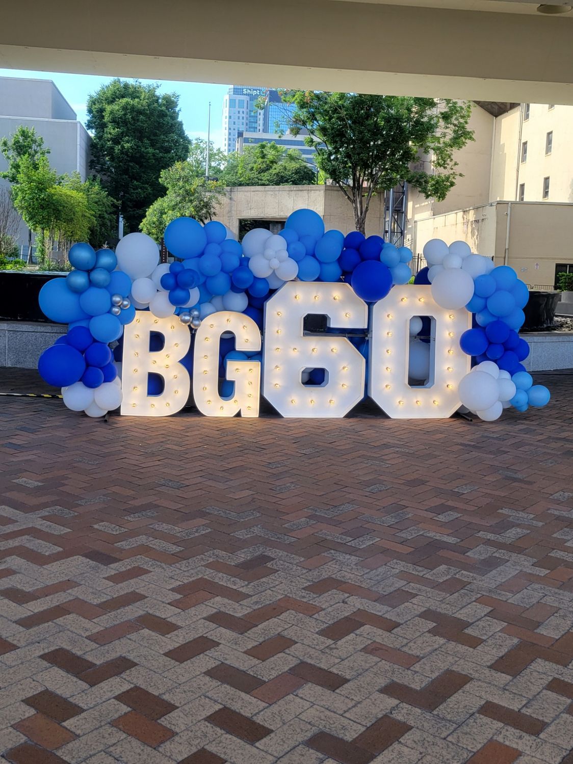 A large sign that says bg60 is surrounded by blue and white balloons.