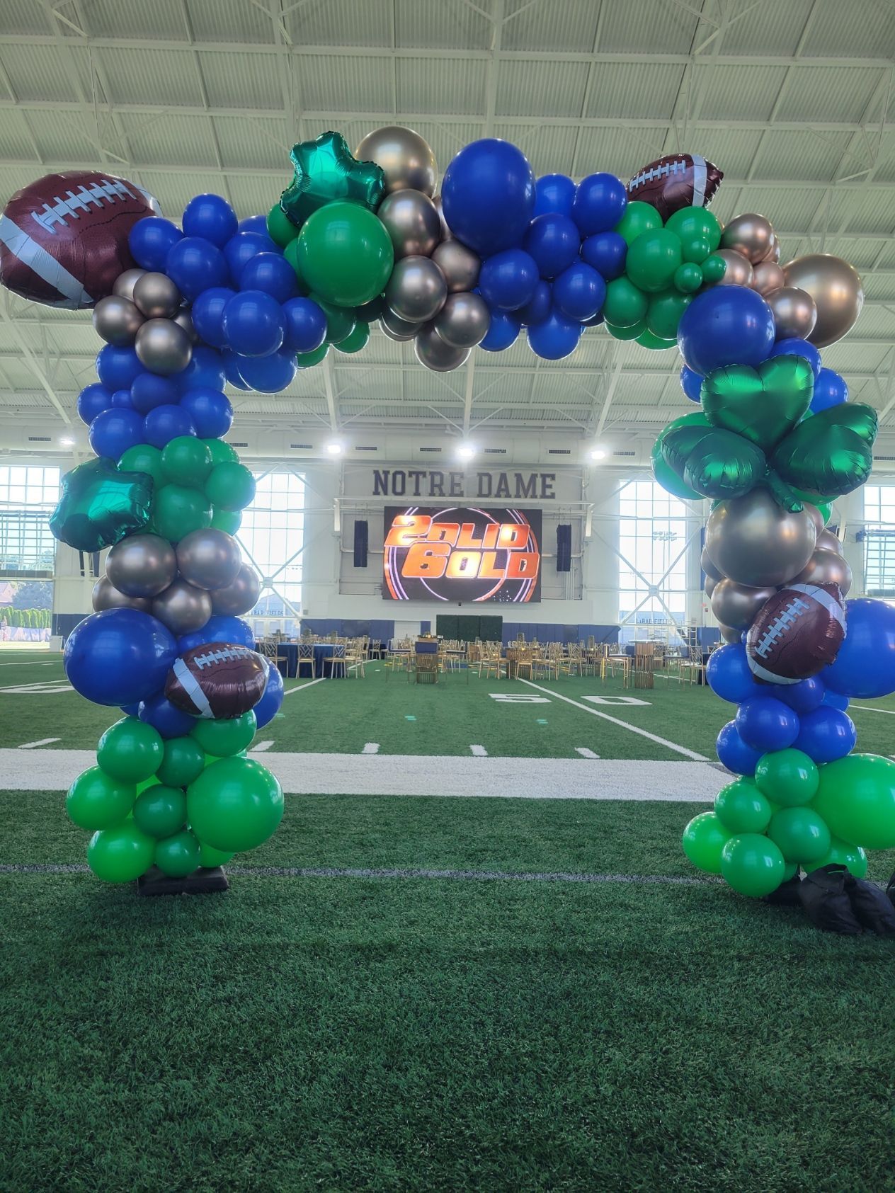 A bunch of balloons are sitting on top of a football field.
