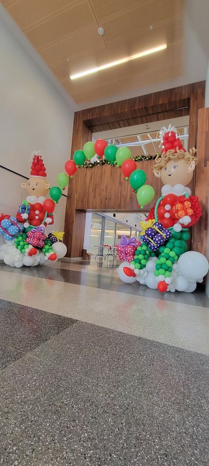 A hallway filled with balloons and decorations for christmas.  Giant elfs