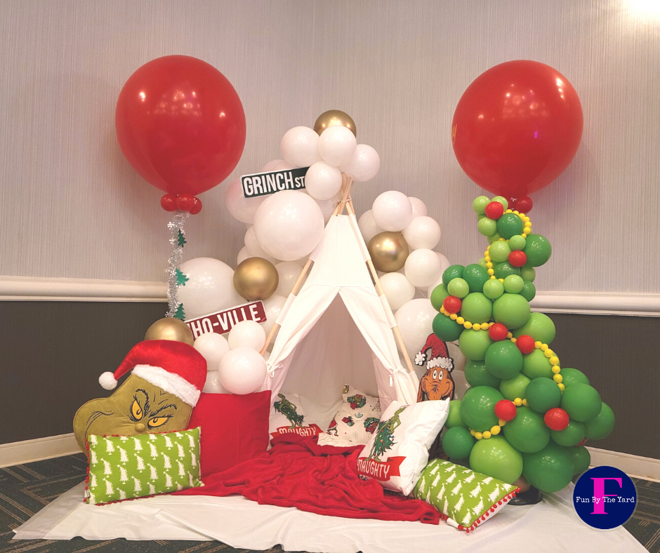 A teepee is surrounded by balloons and a christmas tree.