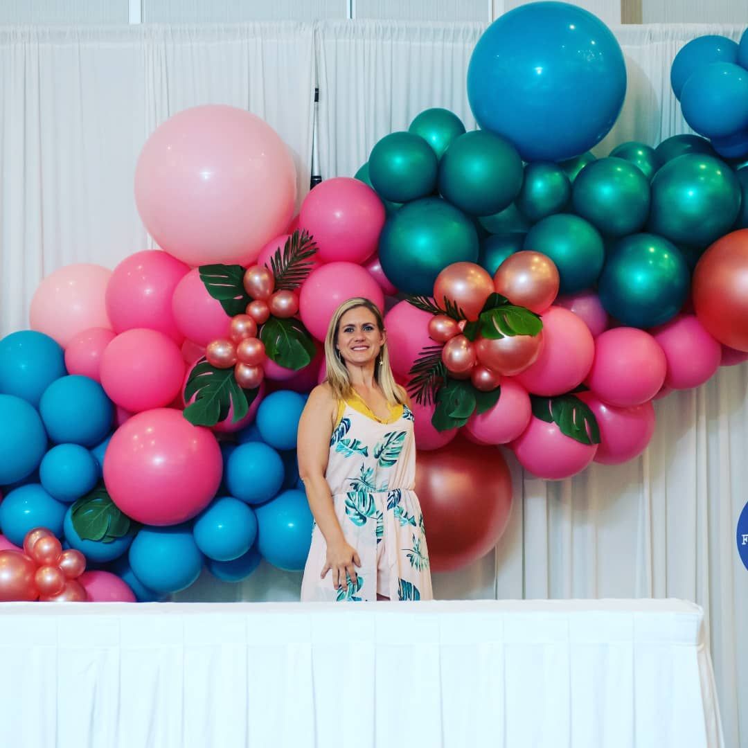 A woman is standing in front of a wall of balloons