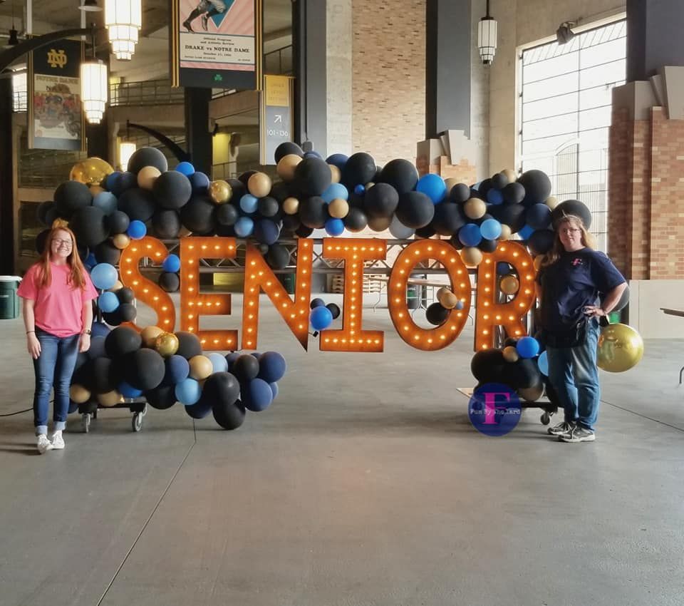 Two people standing in front of a sign that says senior