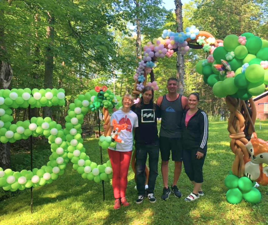 Group of four people posing in front of balloon decorations with a