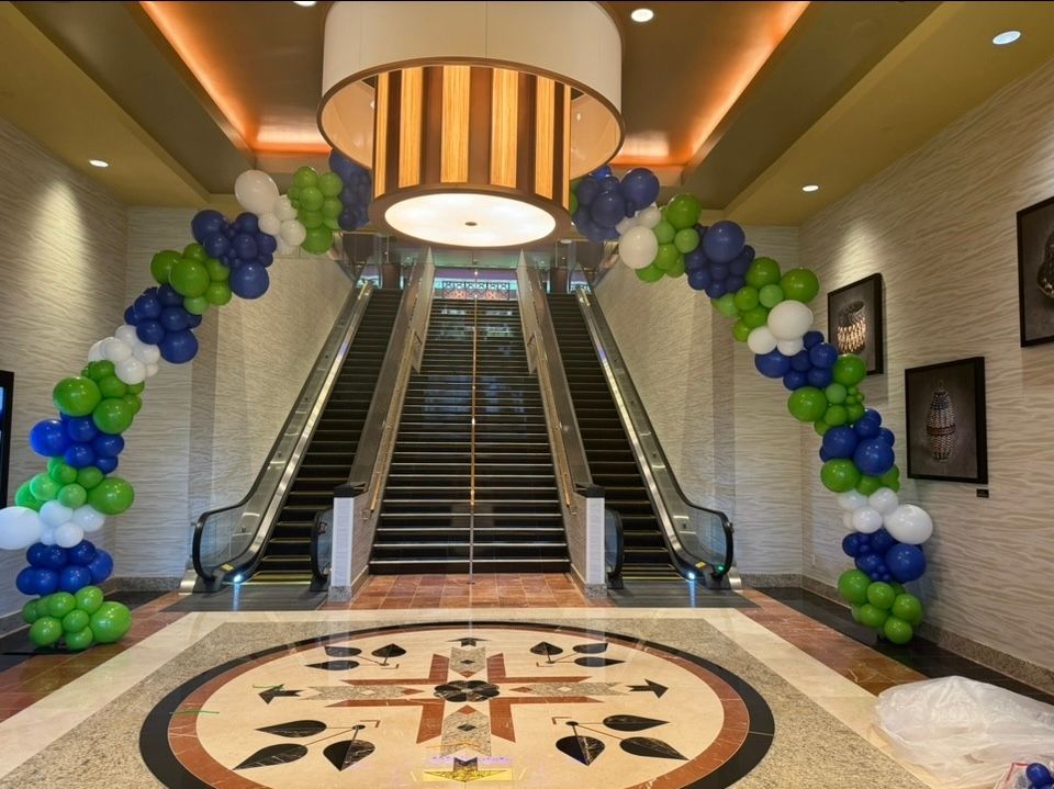 corporate freeform organic balloon arch in green blue and white at Four Winds Casino in South Bend Indiana