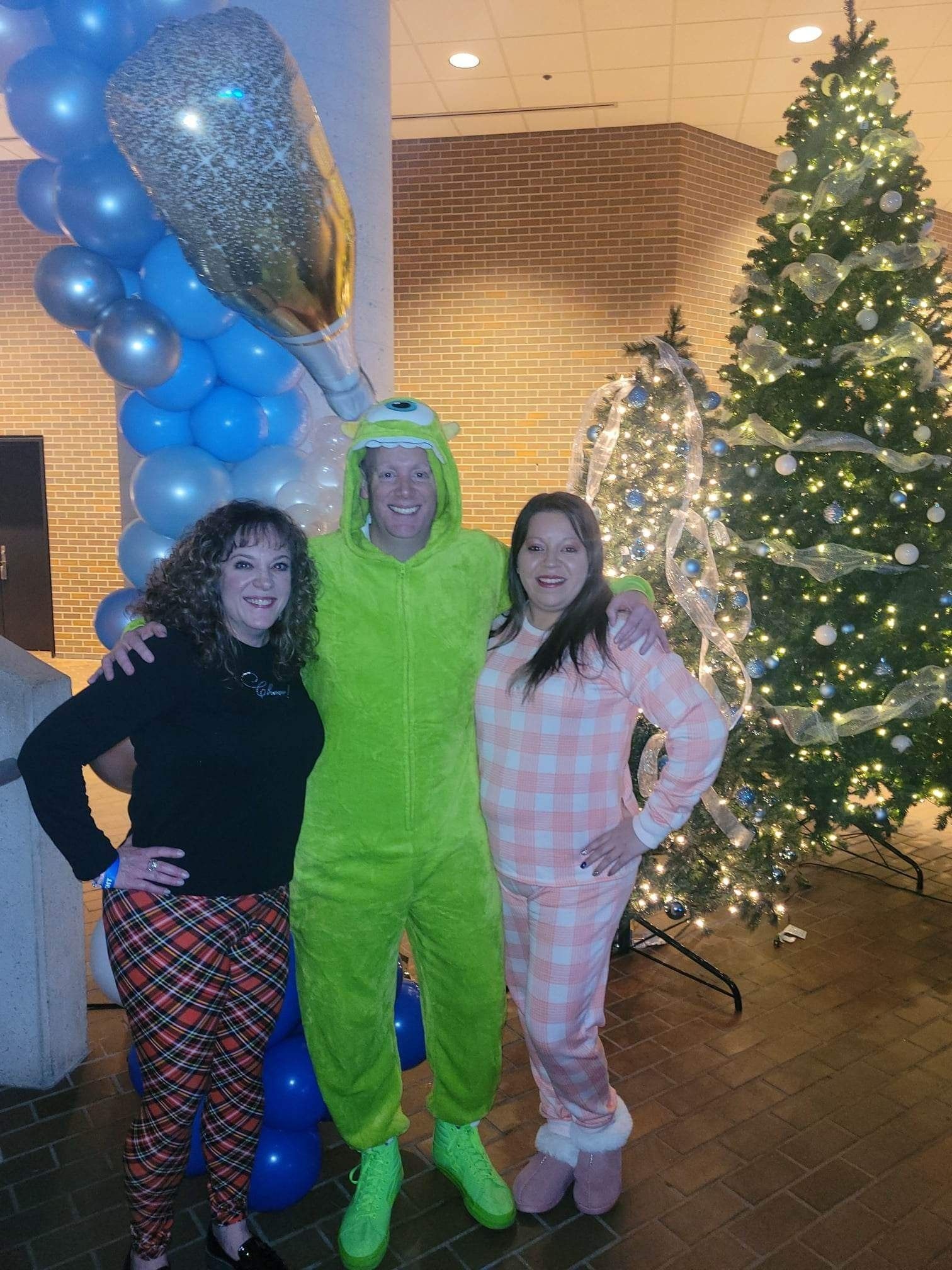 Three people are posing for a picture in front of a christmas tree.