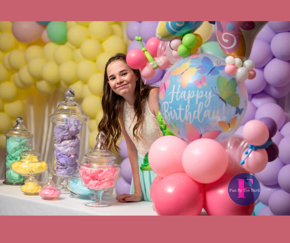 Girl smiling at a birthday party, surrounded by balloons and candy jars.
