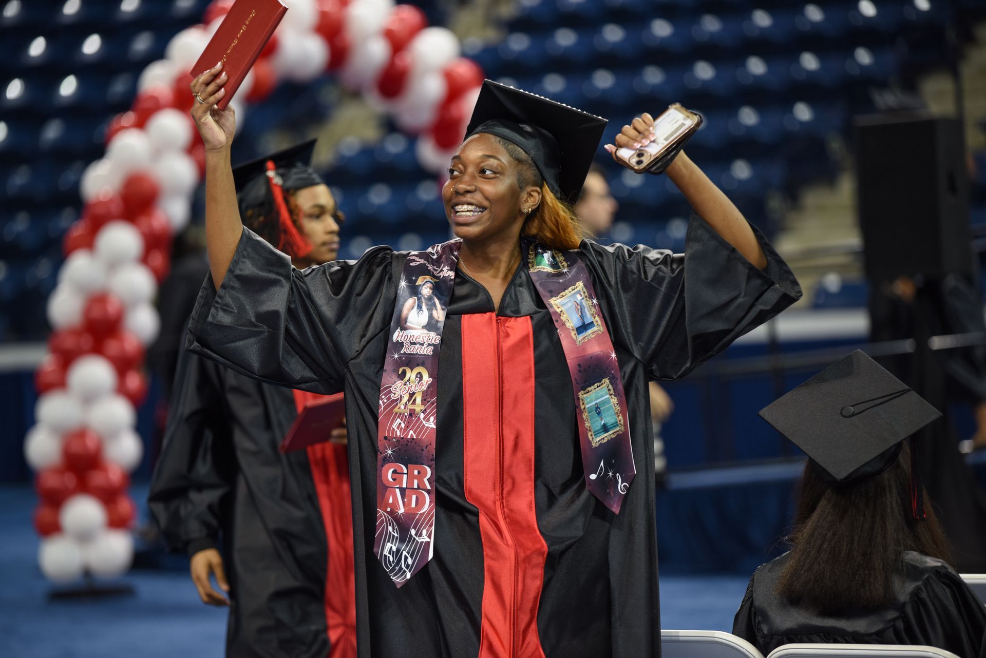 A woman in a graduation cap and gown is holding a diploma in her hand.