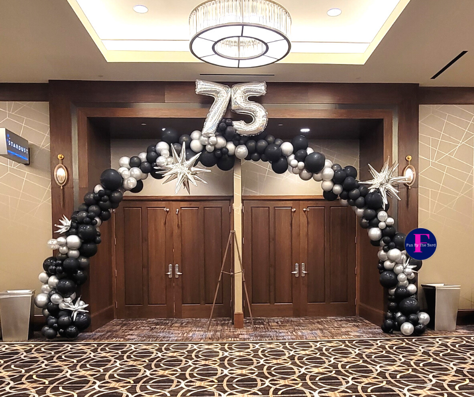 A room with a balloon arch and a number 75 balloon.
