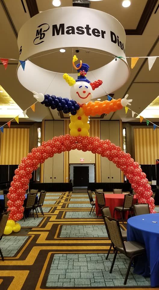 A room with tables and chairs and a clown made out of balloons