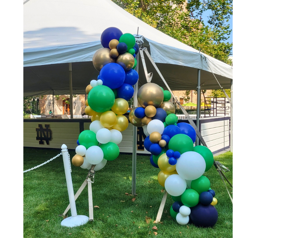 A bunch of balloons are sitting in the grass in front of a tent.