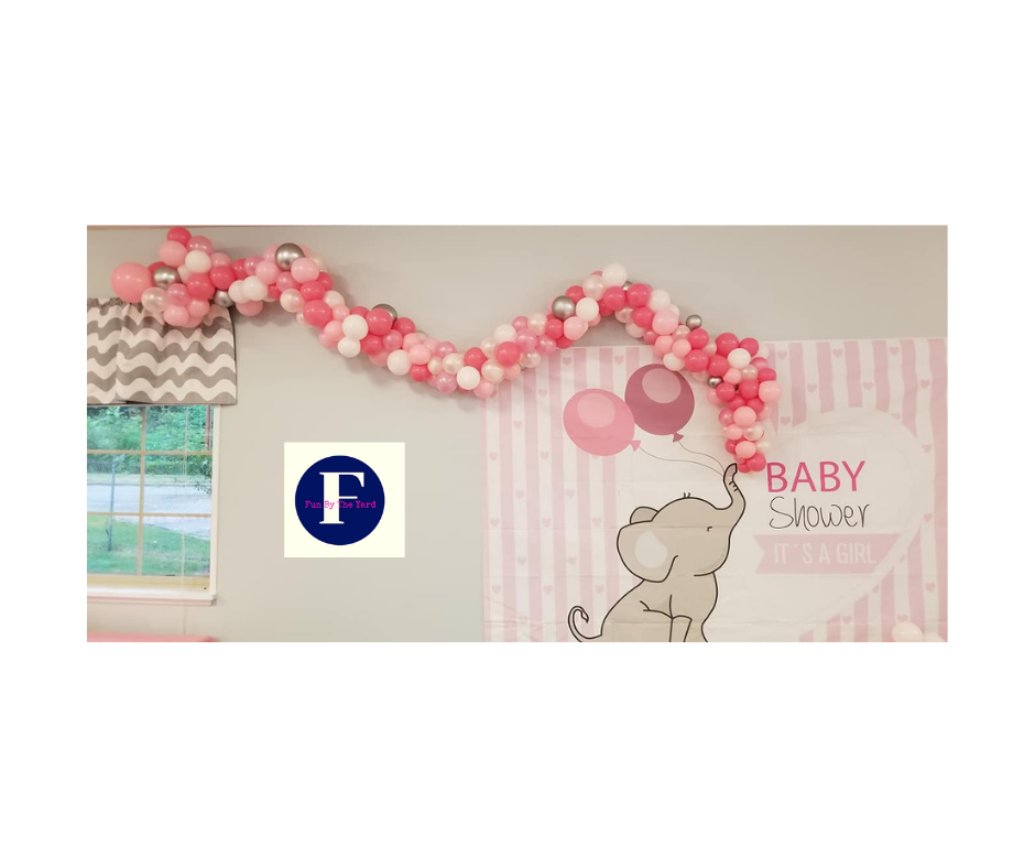 A baby shower with balloons and an elephant on the wall.