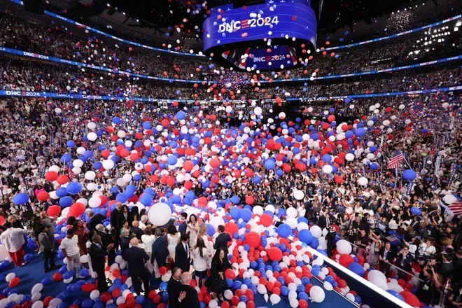 A crowd of people in a stadium with red white and blue balloons.  DNC balloon drop