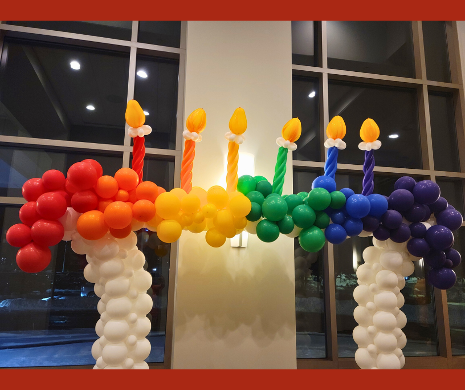 Colorful balloon menorah with rainbow candles.
