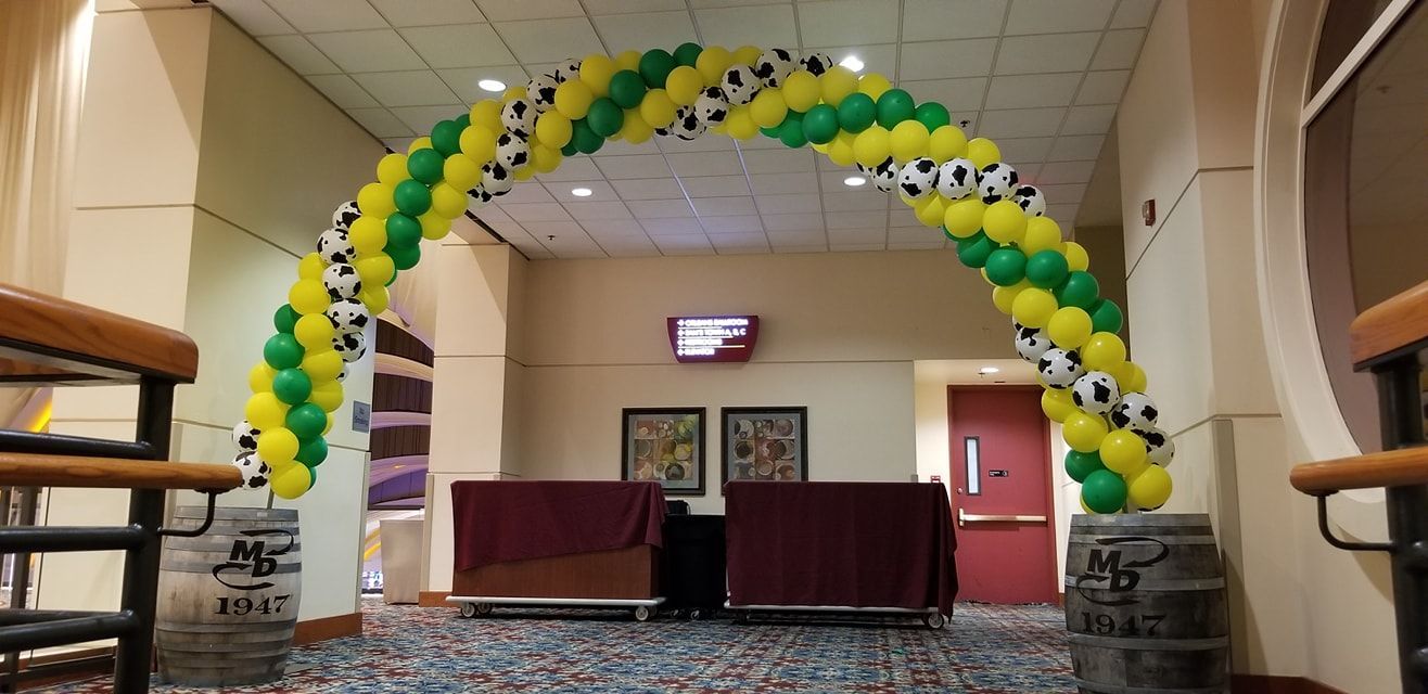 A green and yellow balloon arch in a hallway
