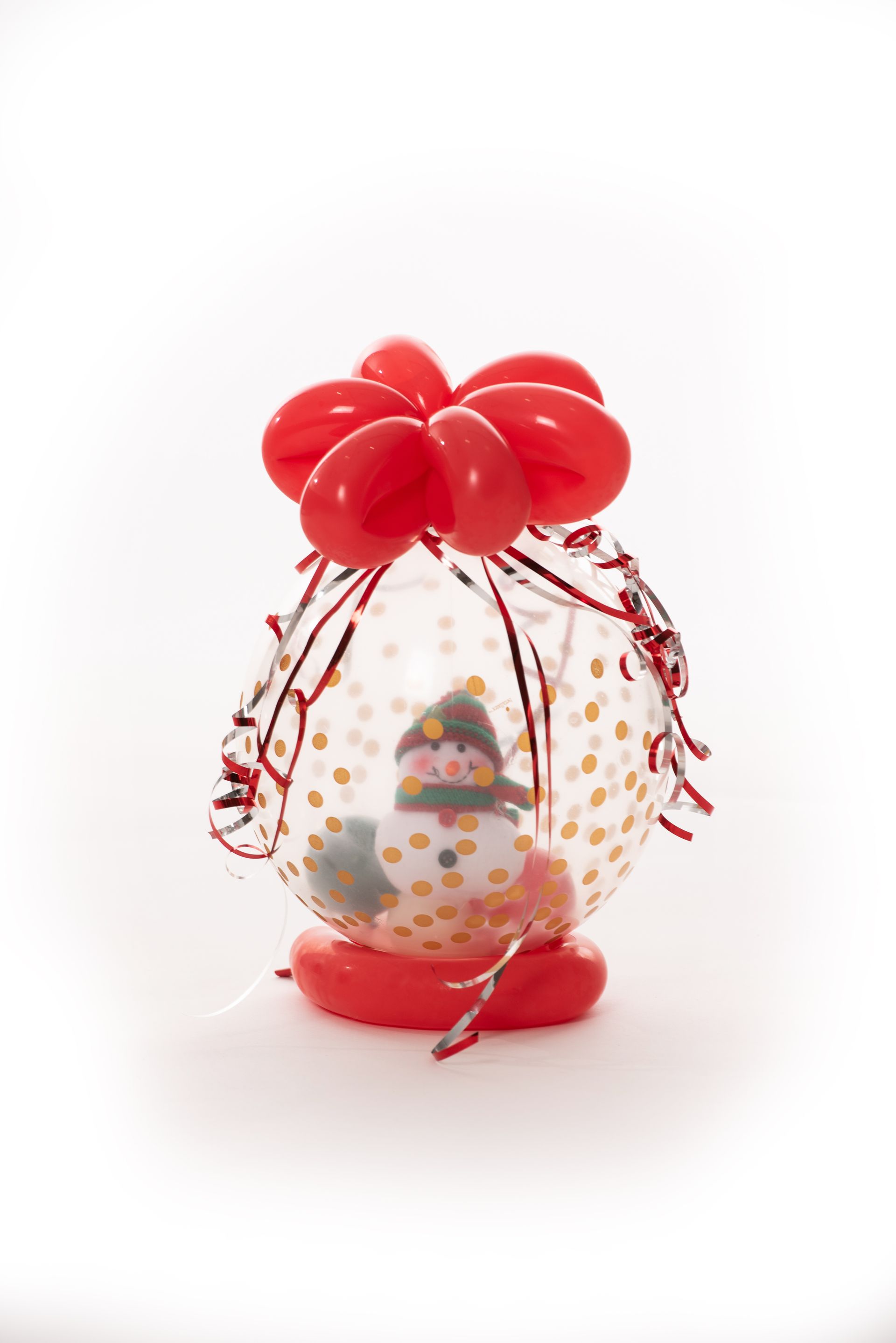 A balloon with a snowman inside of it and red balloons.