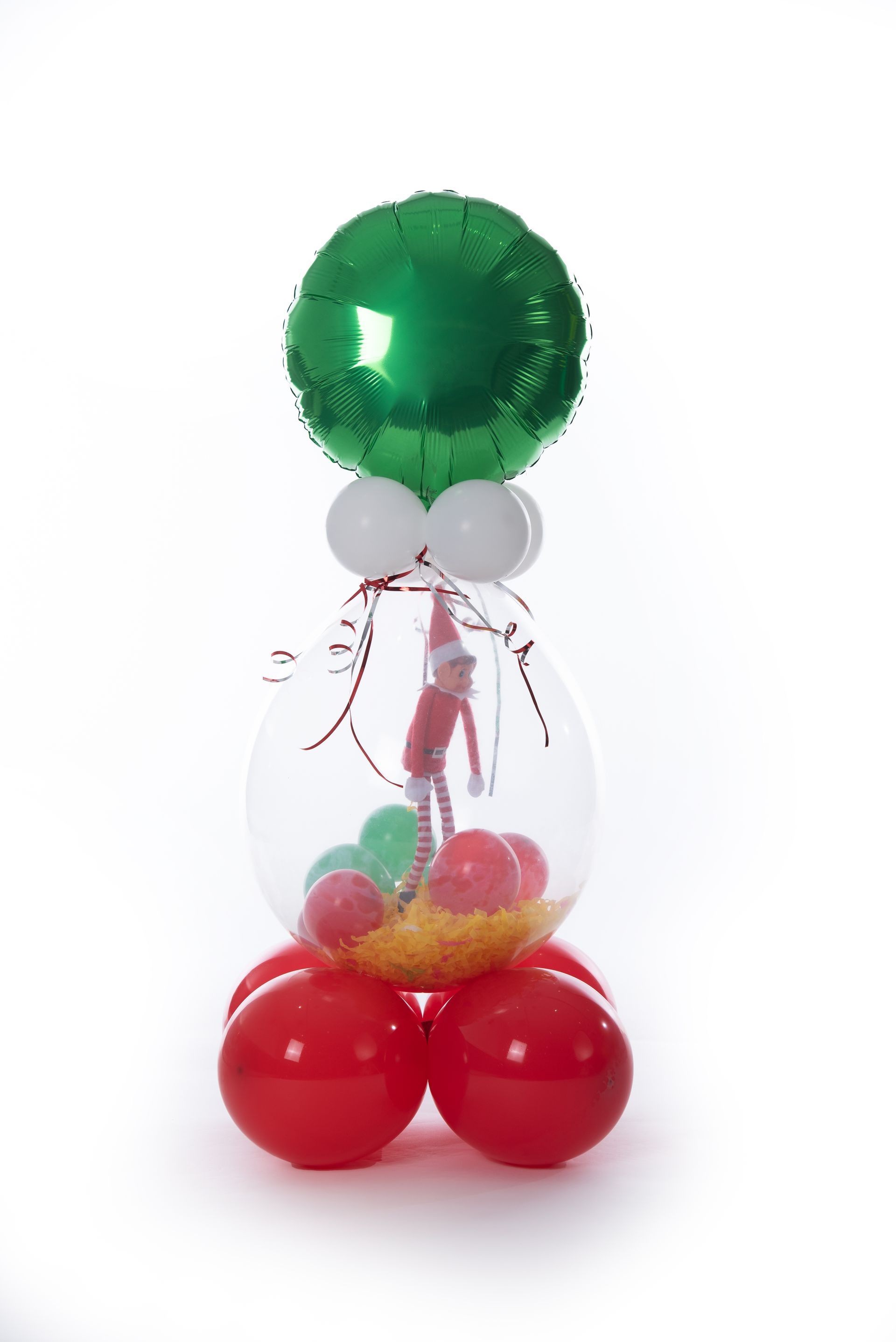 An elf on the shelf is sitting inside of a balloon filled with balloons.
