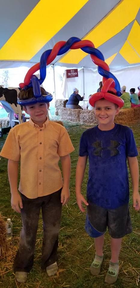 Two boys wearing cowboy hats are standing under a tent. Balloon Twisting Entertainment