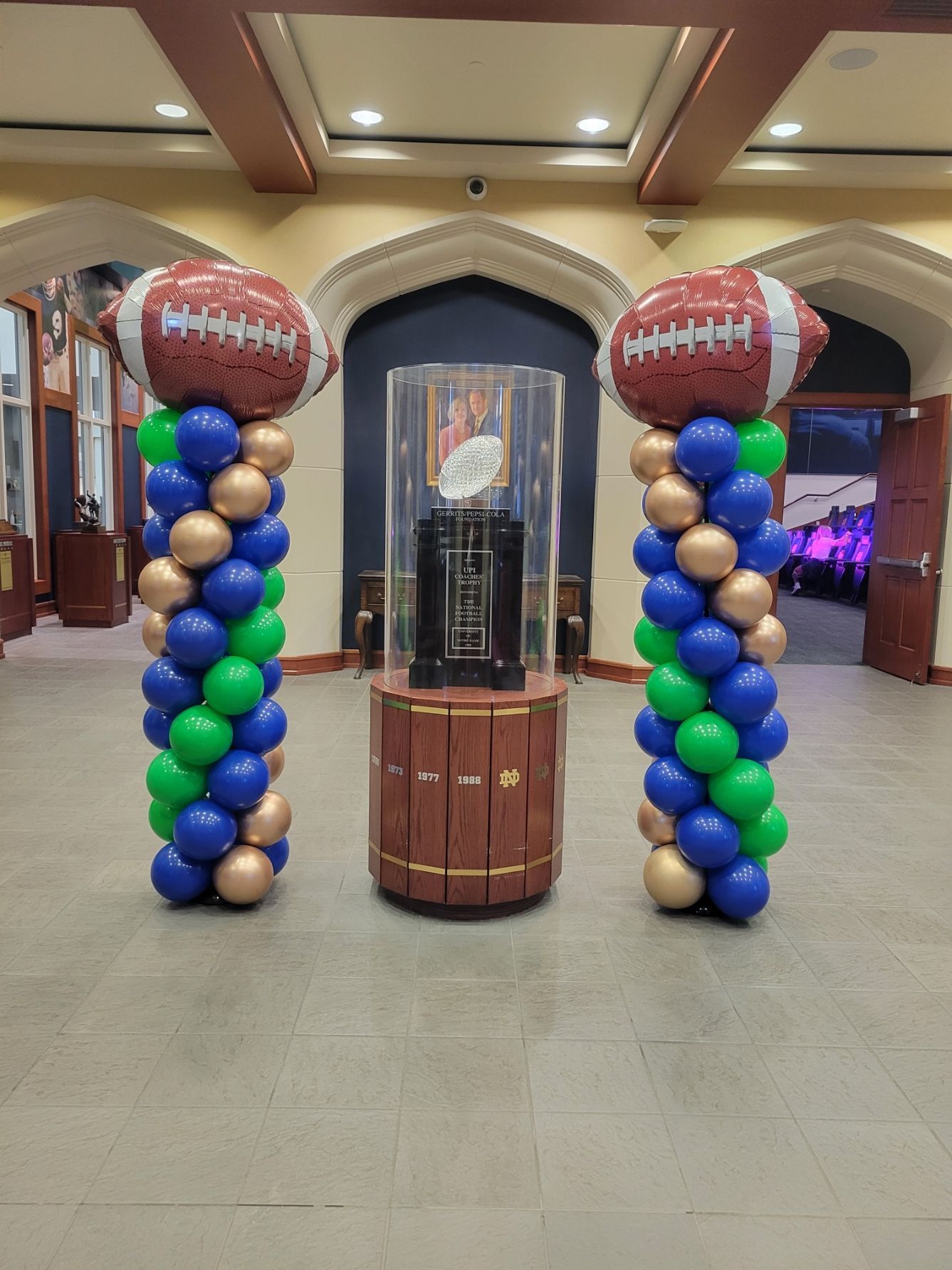 Notre Dame National Championship trophy flanked by balloon columns with football toppers