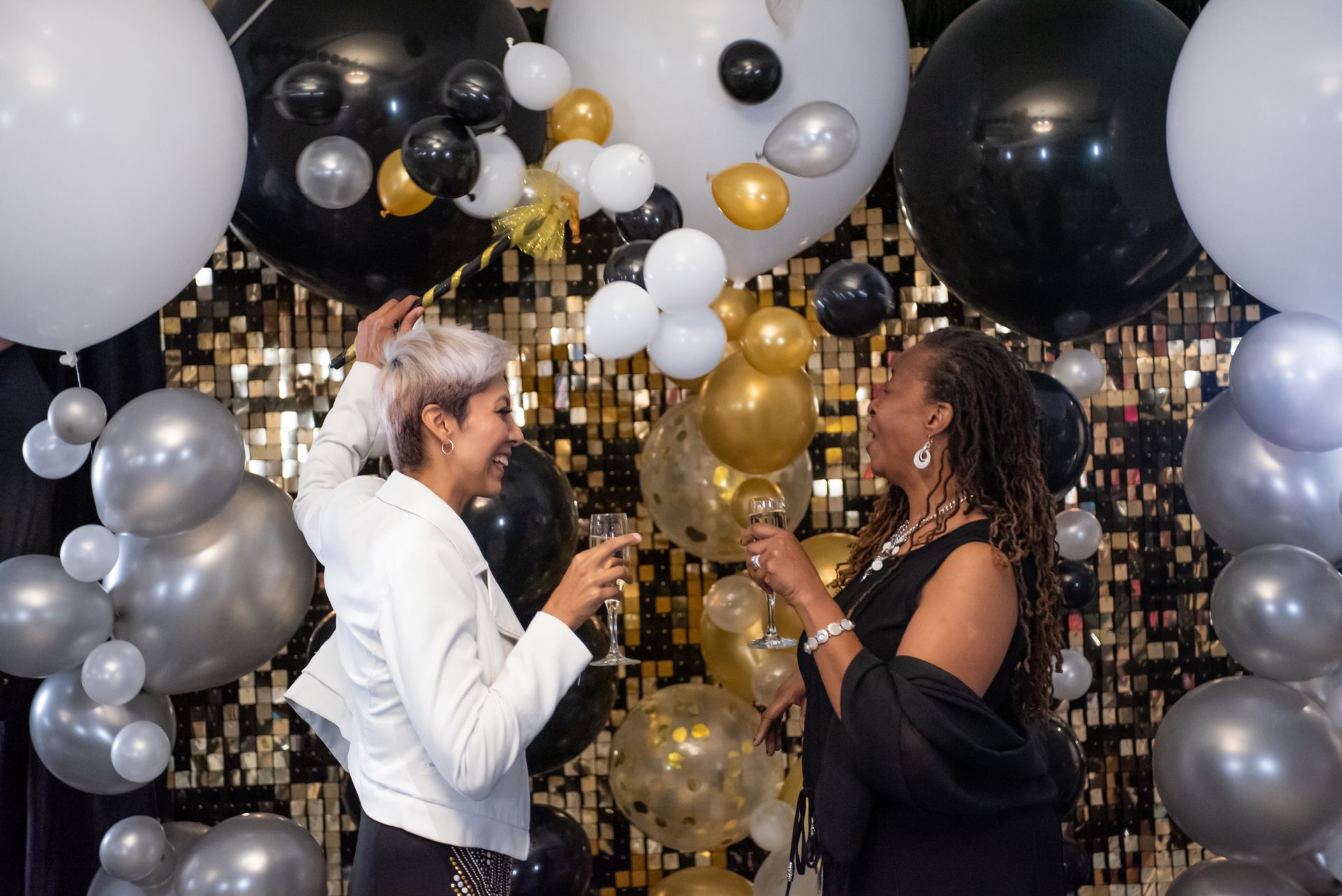 A man and woman are standing in front of a door decorated with balloons.