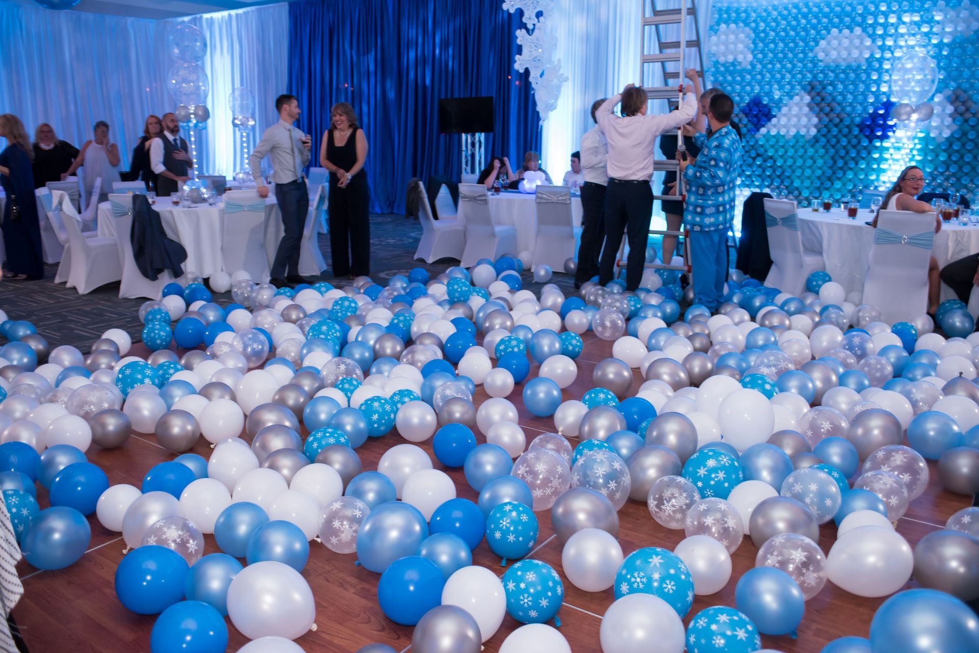 blue, white, and silver balloons on the floor after a balloon drop