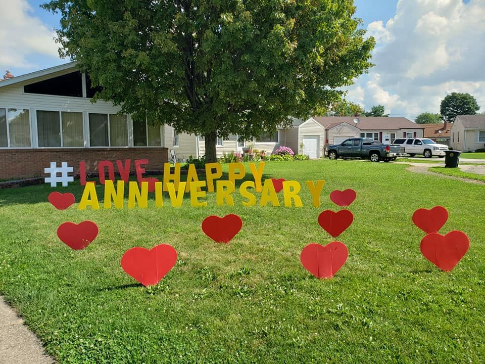 A yard with a sign that says happy anniversary.  Heart themed yard card.