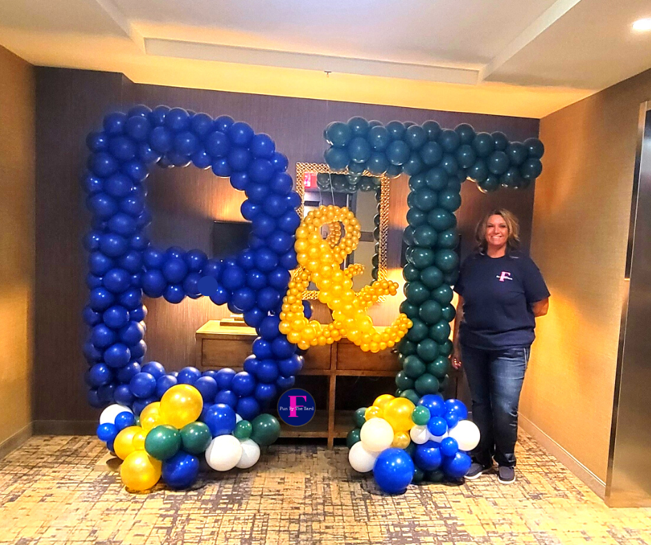 A woman is standing in front of a sign made of balloons.  Barnes and Thronburg