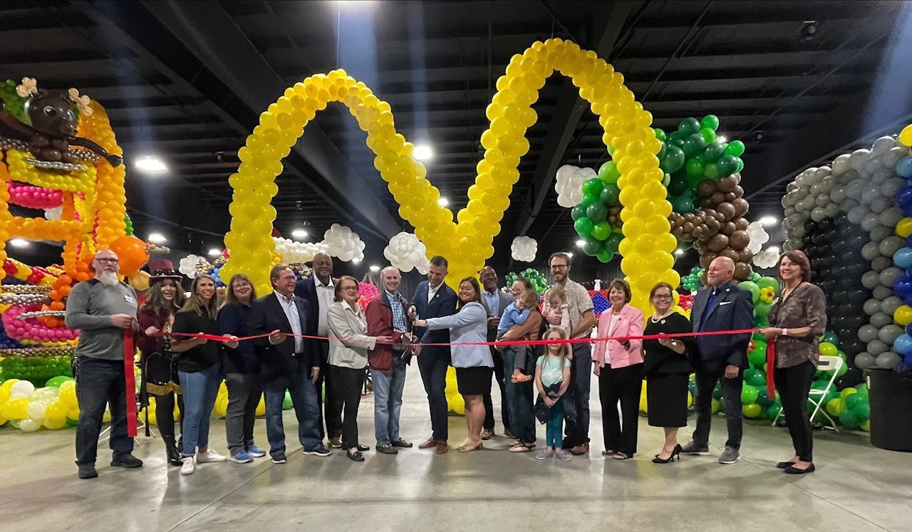 A group of people are standing in front of a mcdonald 's sign made of balloons.