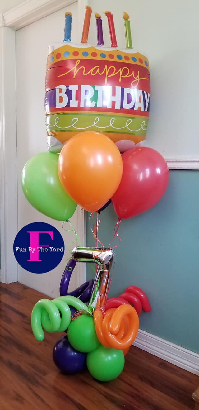A bunch of birthday balloons are sitting on a wooden floor.
