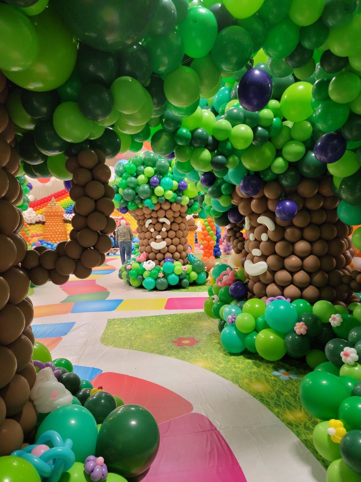 A hallway filled with balloons decorated to look like trees.  Candy Land
