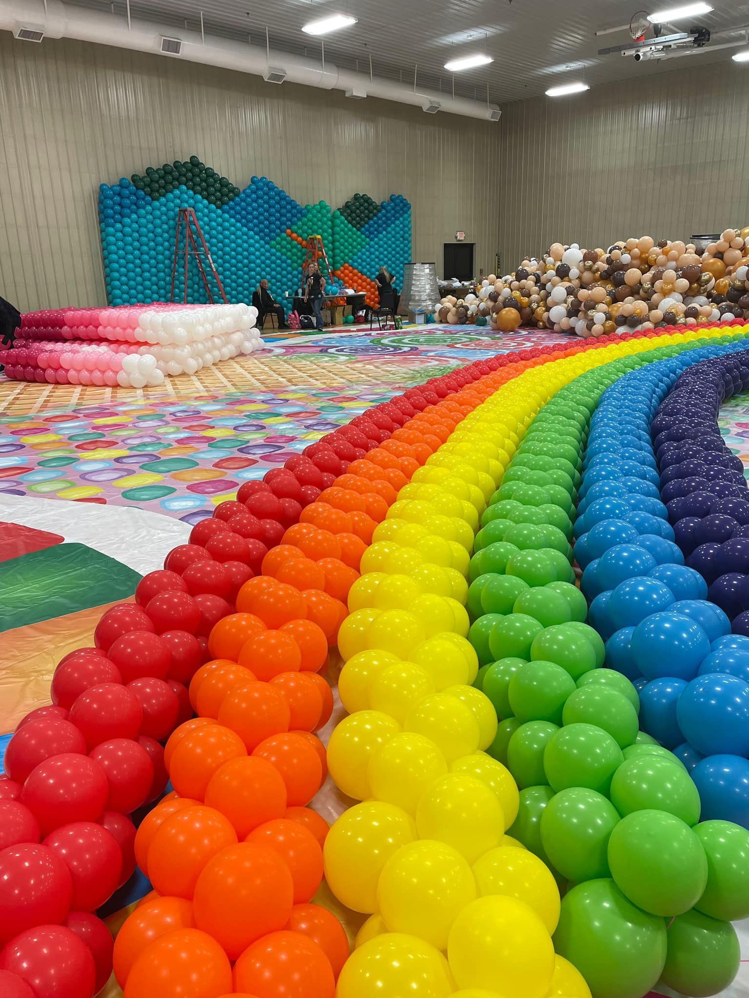 A rainbow made out of balloons in a room.
