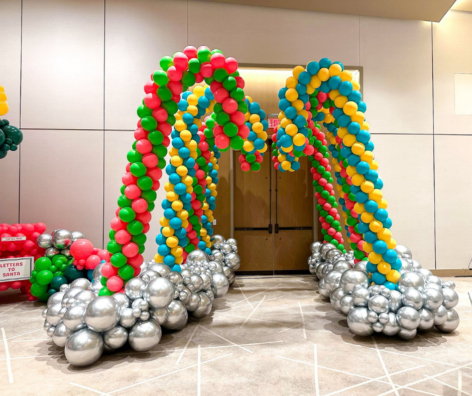 Candy cane balloon arches with silver base, framing a doorway.
