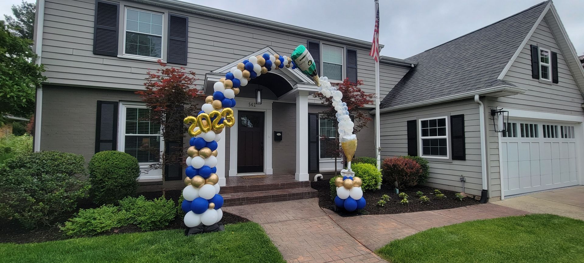 A house with a balloon arch in front of it.