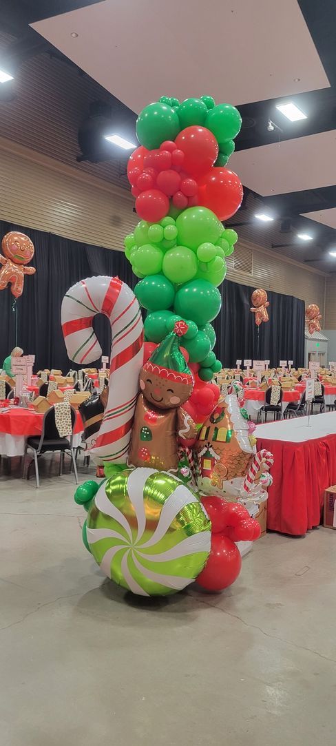 A Christmas balloon sculpture with candy cane, gingerbread, elf, and ornament decorations.