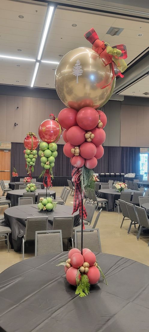 Balloon decorations on tables in a large event space. Gold and pink balloon accents resemble fruit.