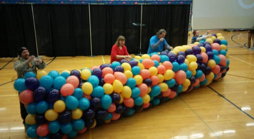 A bunch of colorful balloons are sitting on a wooden floor