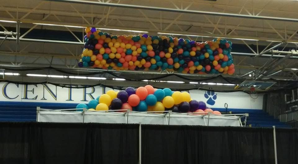 A bunch of balloons are hanging from the ceiling above a sign that says centre